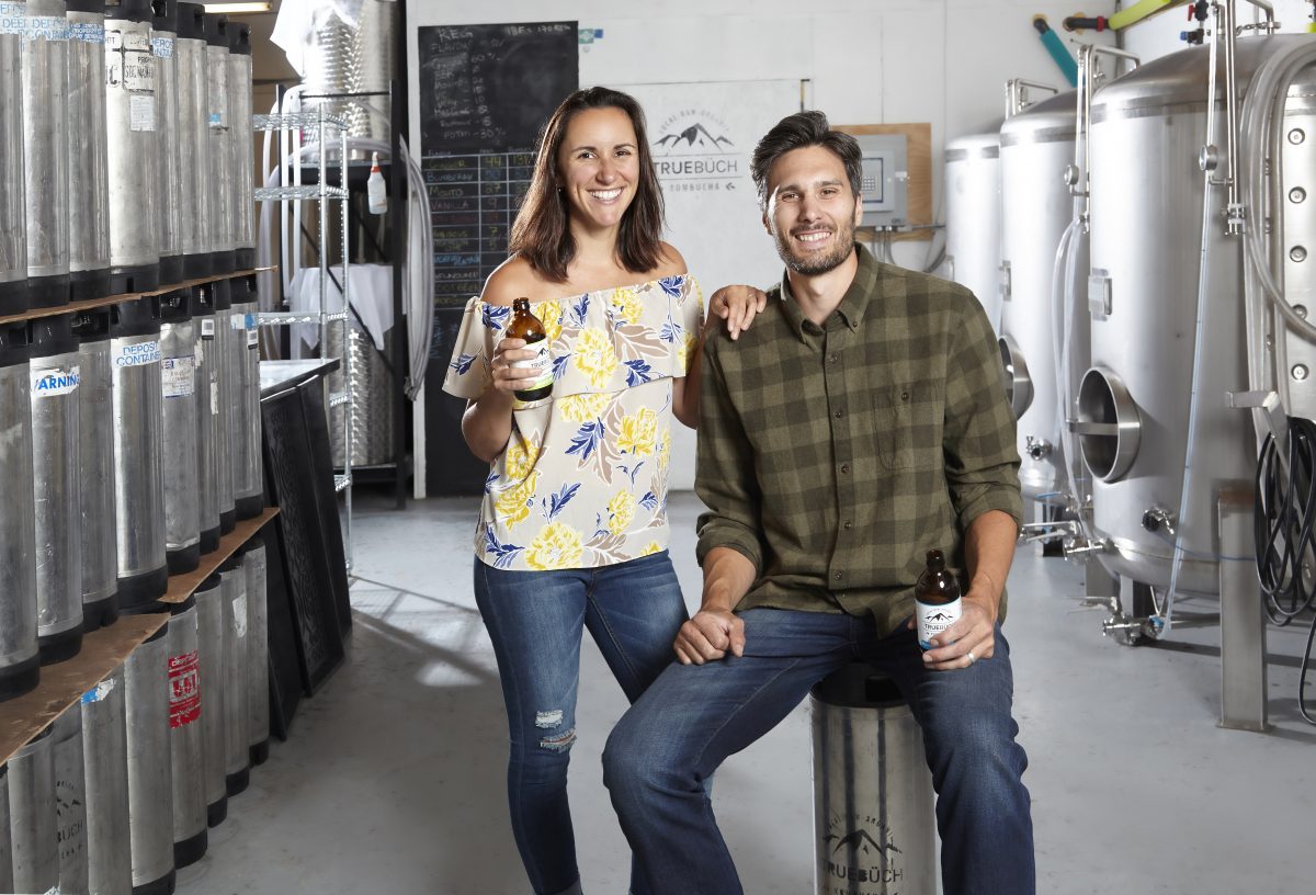 Louisa Ferrel CPA, CA and Conrad Ferrel CPA, CA pose in their workroom, each with a bottle of True Buch in their hands.