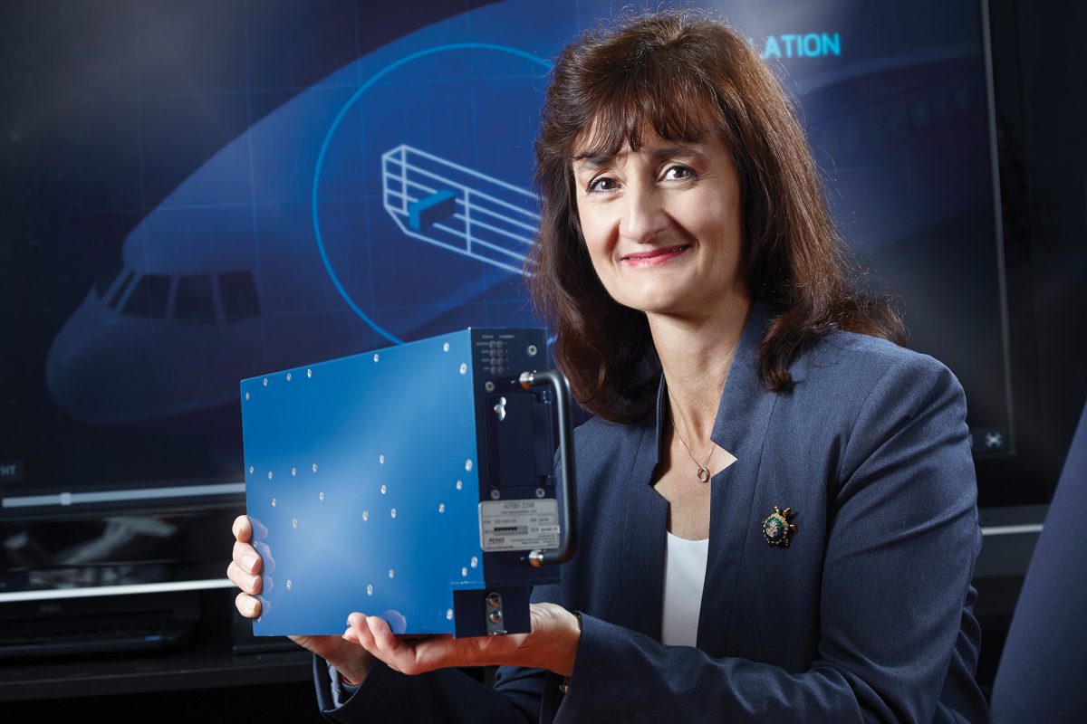 Nola Heale CPA, CA smiles at the camera while holding a piece of tech.