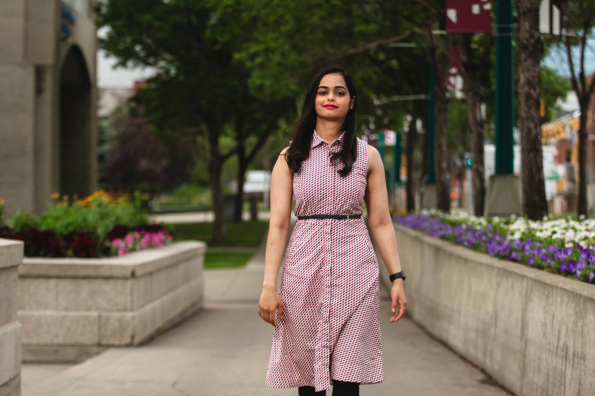 Priya Joshi walks toward the camera. MacEwan University is in the background.