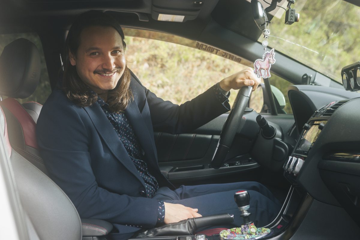 Roy Twinn CPA smiles at the camera from inside a car. His hand is on the steering wheel, and he is leaning forward slightly.