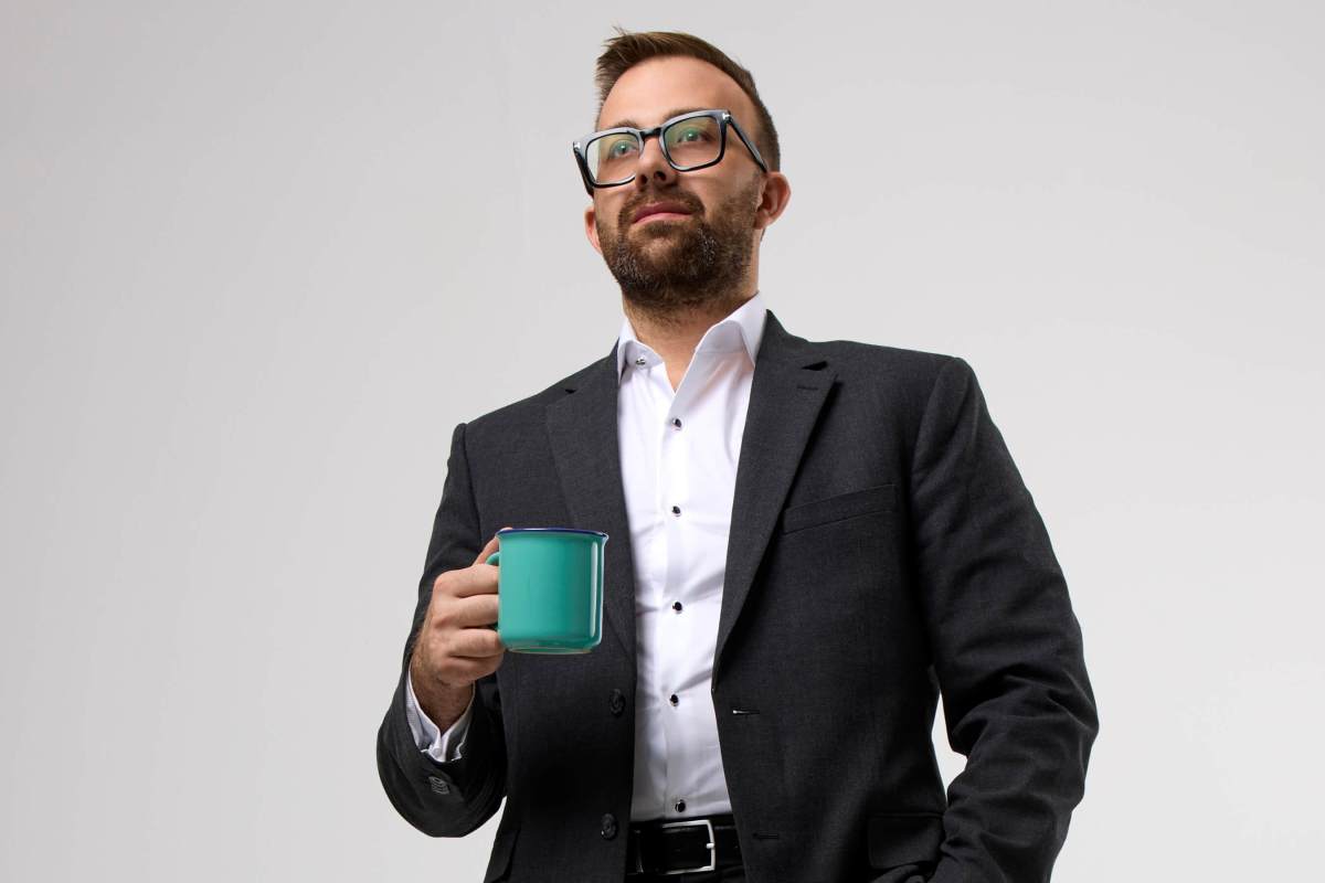 Aneese holds a coffee cup and looks off camera.
